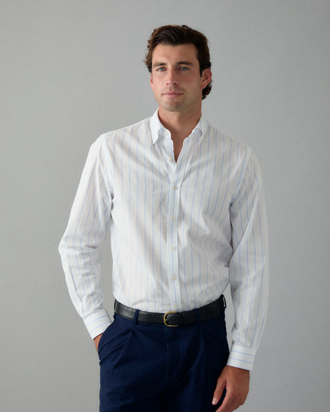 Man wearing a white striped shirt and dark pants against a gray background