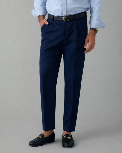 Person wearing navy trousers with a light blue shirt on a gray background