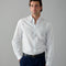 Man wearing a white striped shirt and dark pants against a gray background