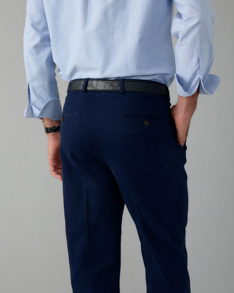 Person wearing a light blue shirt and navy pants on a gray background