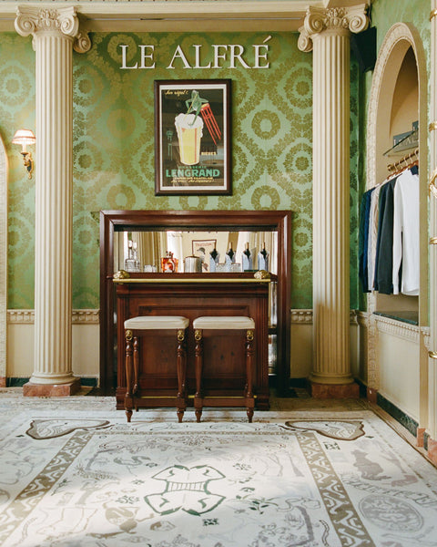 Decorative interior with green wallpaper, wooden bar, and framed picture.