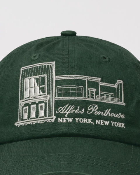 Green cap with embroidered design and text on a light gray background