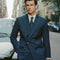 Man in a blue suit standing on a city street with cars and buildings in the background